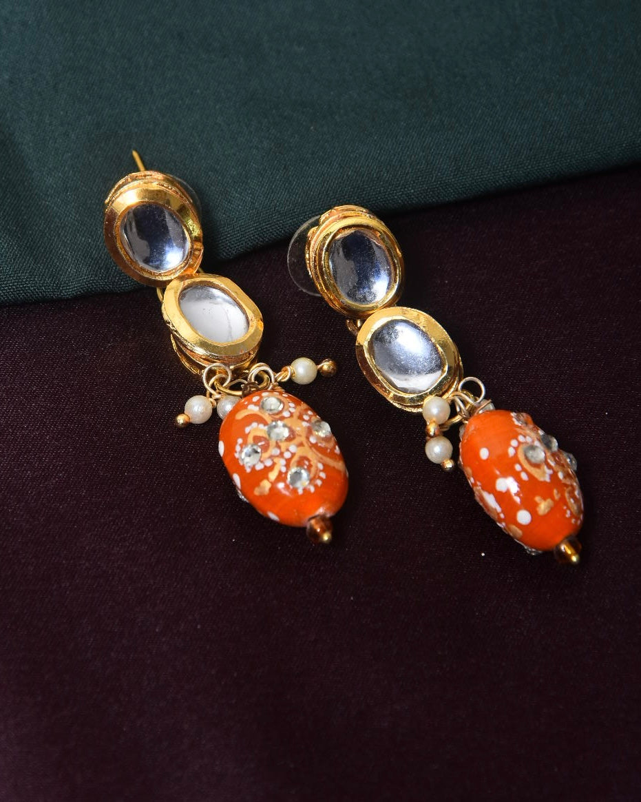 A pair of gold earrings with orange beads and small white pearls.