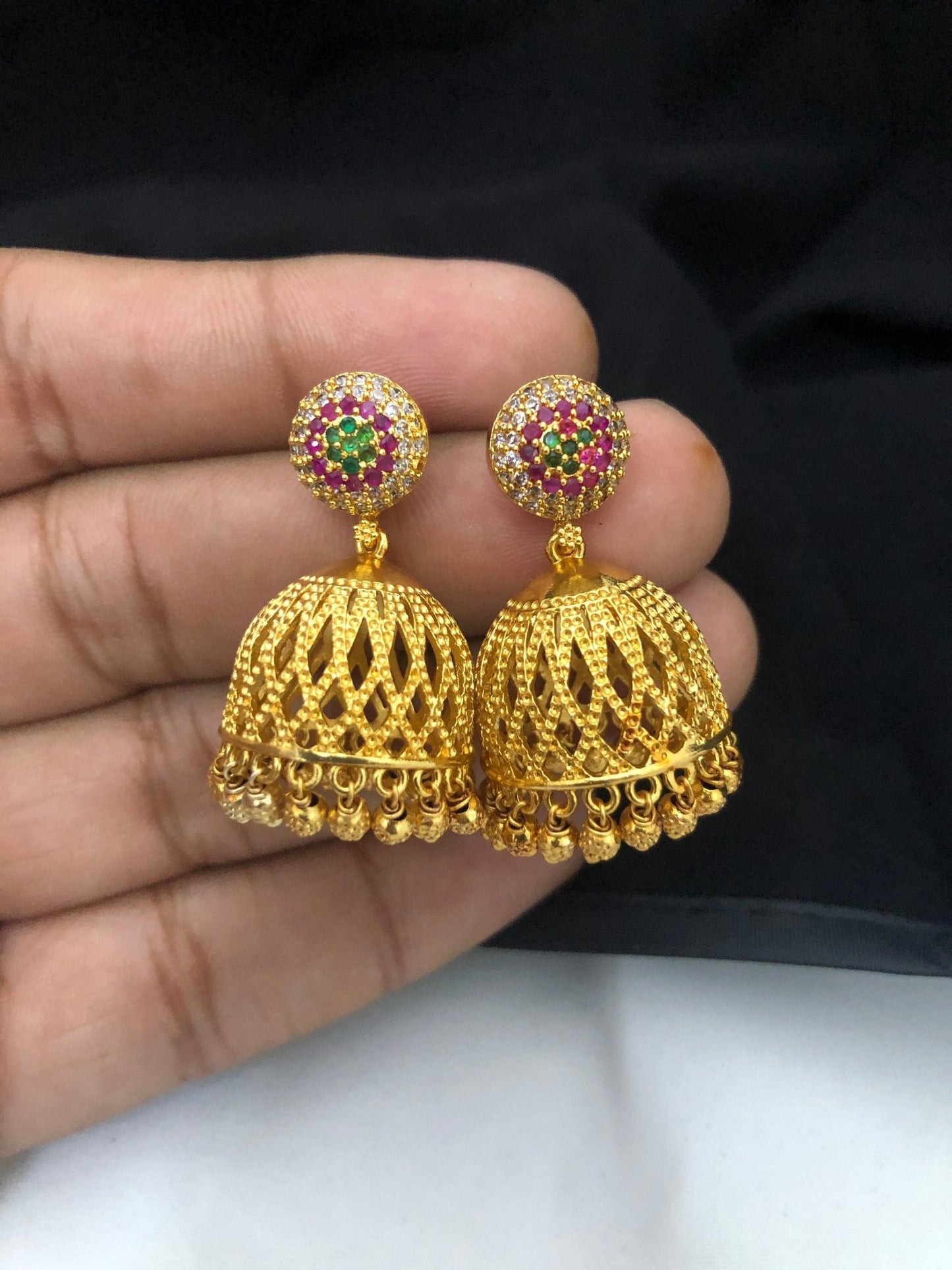 Gold jhumka earrings with intricate lattice design and colorful gemstone accents.