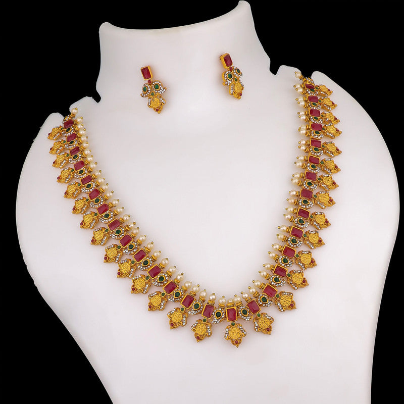 A gold necklace with red and white stones, featuring intricate designs, displayed on a mannequin bust, accompanied by matching earrings.