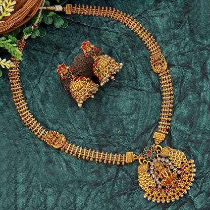 A set of traditional gold jewelry with intricate designs, featuring a necklace and matching earrings on a textured green background.