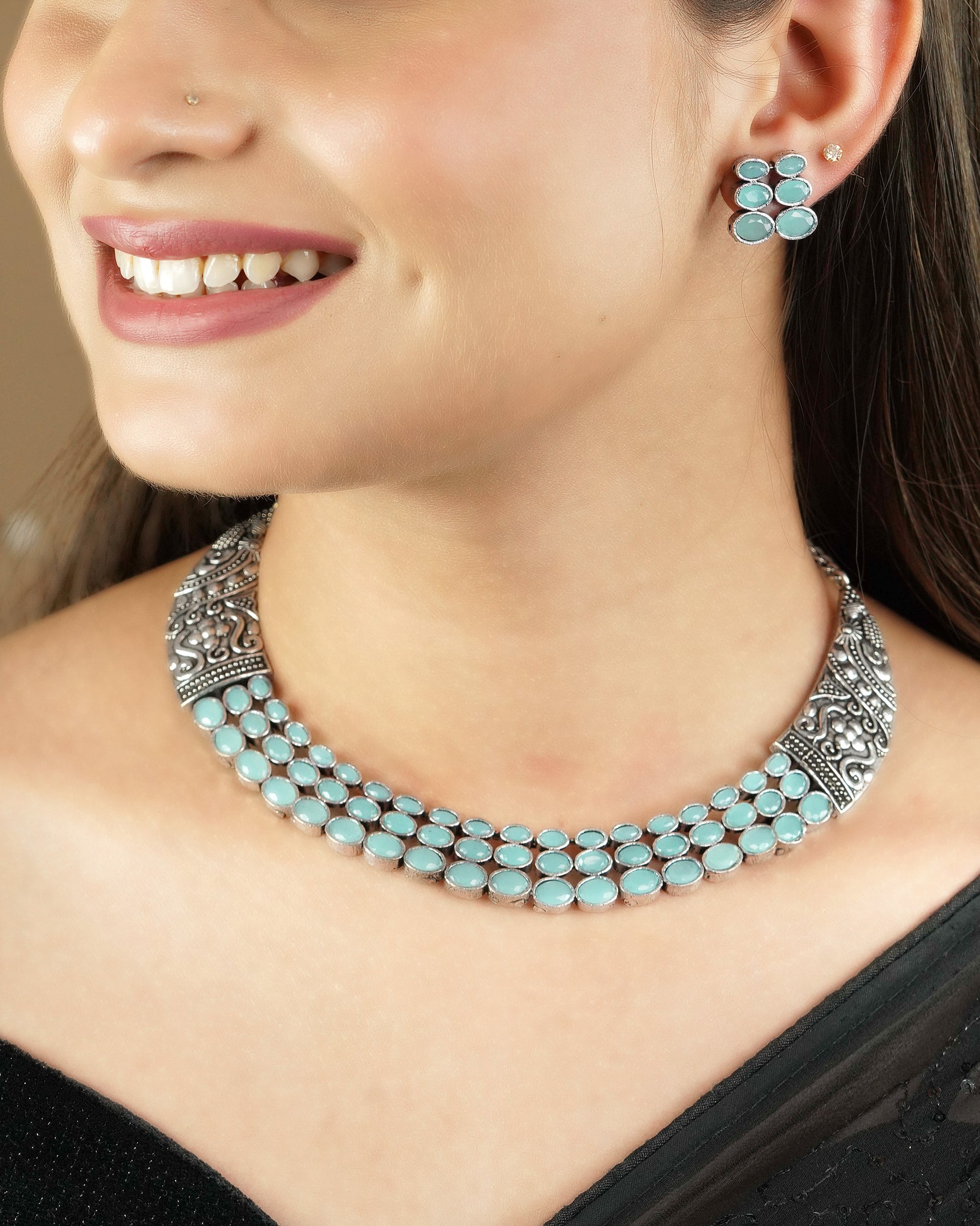 A woman wearing a silver necklace with turquoise stones and matching turquoise stone earrings.