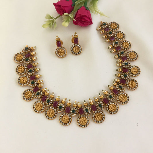 Gold necklace with intricate designs, red and green gemstones, and matching earrings.