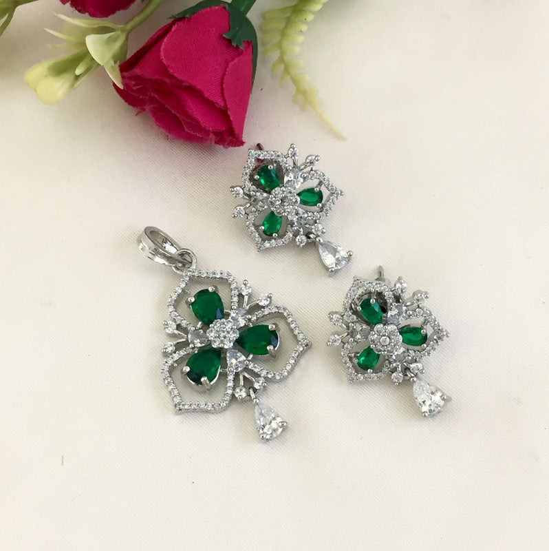 A jewelry set featuring a pendant and matching earrings with green gemstones and clear crystals in a floral design.