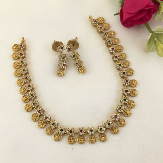 Gold necklace and matching earrings with intricate designs and colorful gemstone accents.