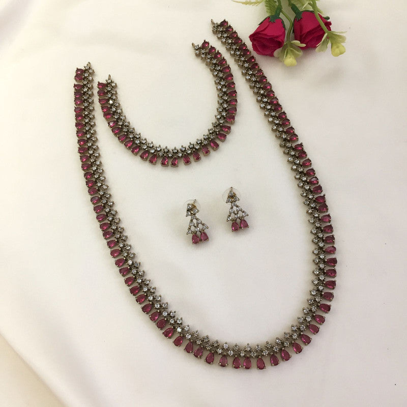 A jewelry set featuring a necklace, a bracelet, and a pair of earrings with red and white stones.