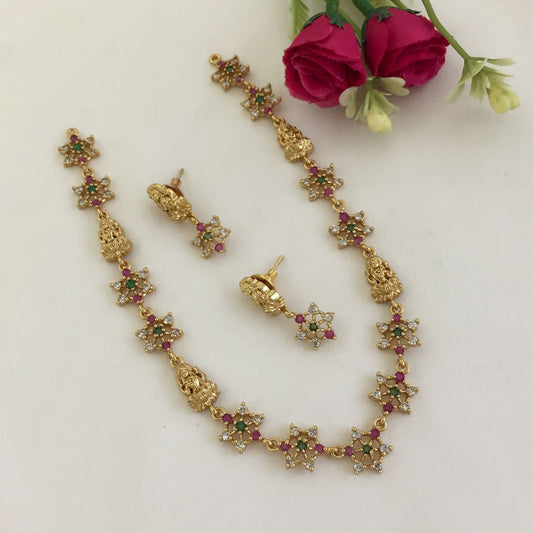 Gold necklace and earrings set with star-shaped designs adorned with colorful gemstones.