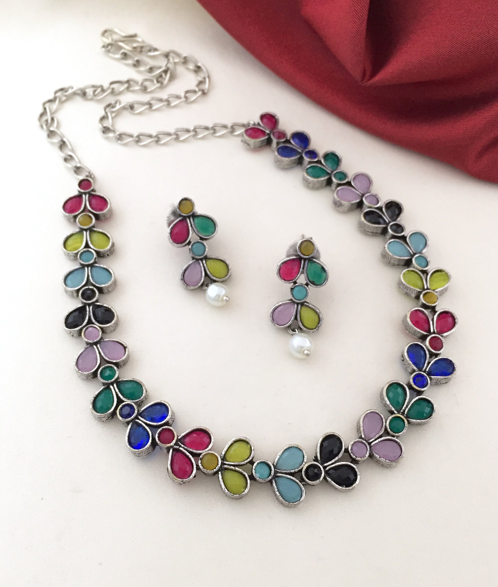 A colorful floral necklace and matching earrings set with multicolored petals and pearl accents.