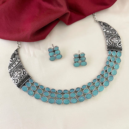 A silver necklace with intricate designs and multiple turquoise stones, accompanied by matching turquoise stone earrings.