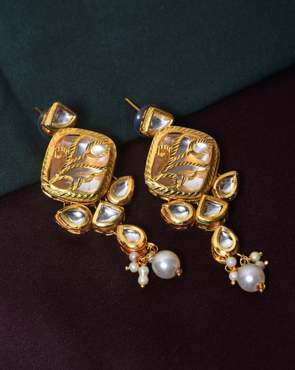 A pair of gold-toned earrings with intricate designs, featuring white gemstones and pearl accents.