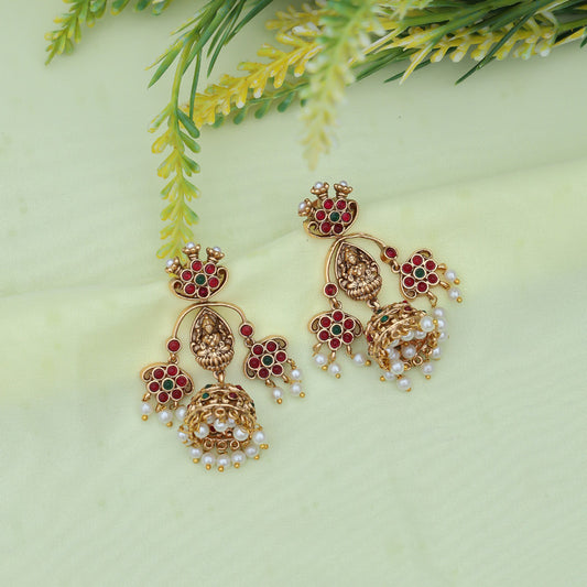 Traditional gold-plated jhumka earrings featuring intricate floral designs adorned with vibrant red and white stones.