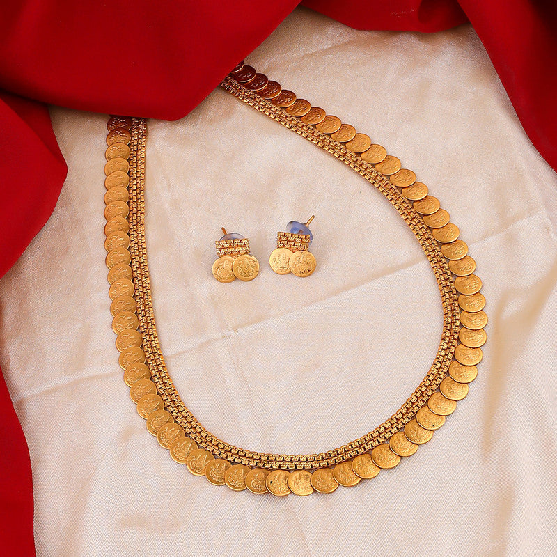 A gold coin necklace and matching earrings displayed on a cream fabric with a red cloth backdrop.