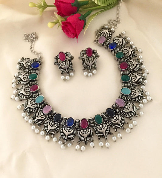 A silver necklace set with colorful gemstones and matching earrings.