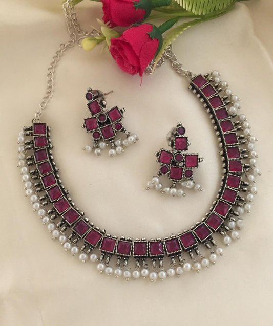 A necklace and matching earrings set featuring square-shaped magenta stones and pearl accents.