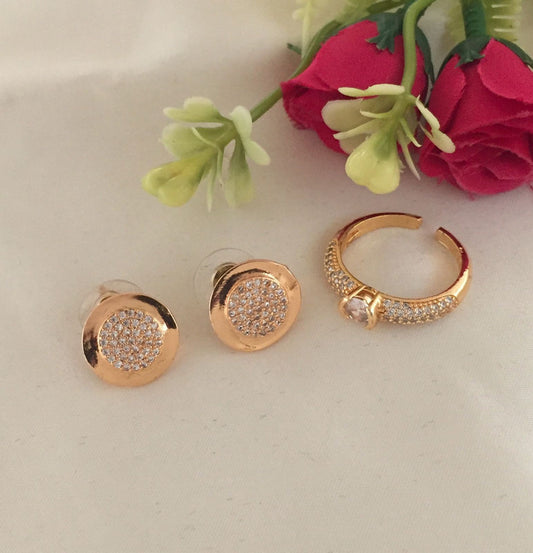 A pair of gold stud earrings with a circular design encrusted with small crystals, and a matching gold ring with crystal accents.