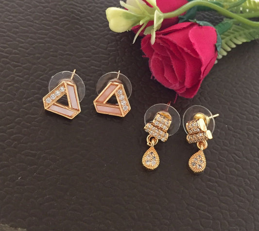 Two pairs of gold earrings, one with geometric shapes and pink inlays, and the other with teardrop-shaped dangles and embedded crystals.