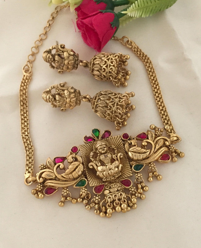 Gold necklace with intricate design featuring a central deity figure, accompanied by matching jhumka earrings.