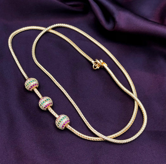 A gold necklace with three spherical beads adorned with multicolored gemstones.